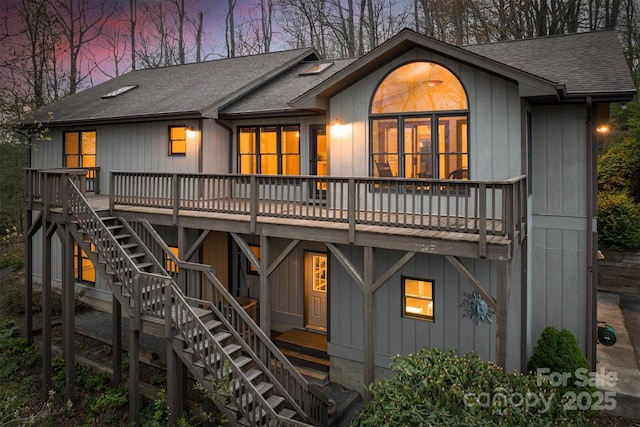 back of property with stairs, a shingled roof, and a wooden deck