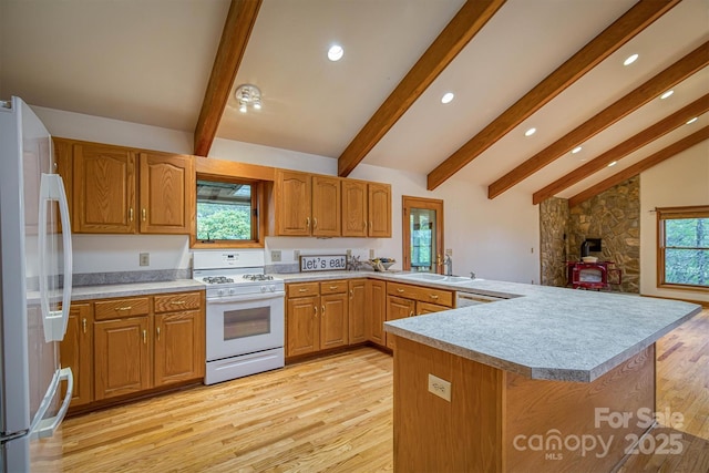 kitchen featuring a peninsula, a sink, lofted ceiling with beams, white appliances, and light wood-style floors
