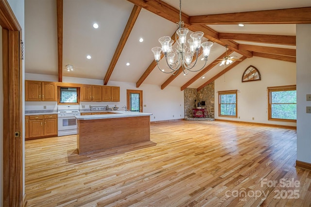 kitchen with white range, light wood-type flooring, a healthy amount of sunlight, open floor plan, and light countertops