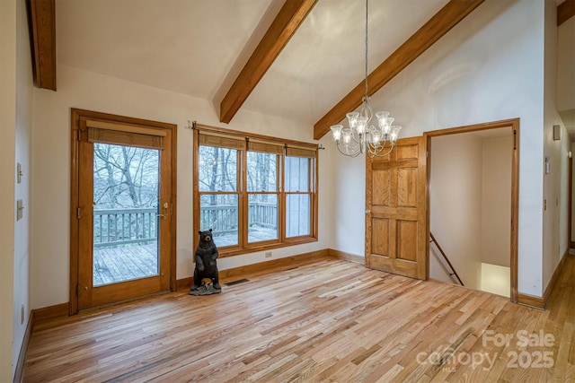 interior space with wood finished floors, lofted ceiling with beams, a healthy amount of sunlight, and a notable chandelier