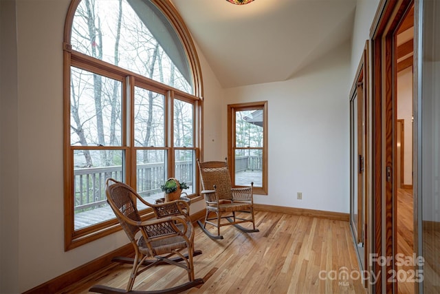 sitting room featuring baseboards, light wood-style flooring, and high vaulted ceiling