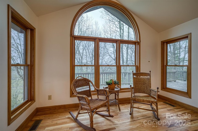 sitting room with lofted ceiling, light wood-type flooring, plenty of natural light, and baseboards