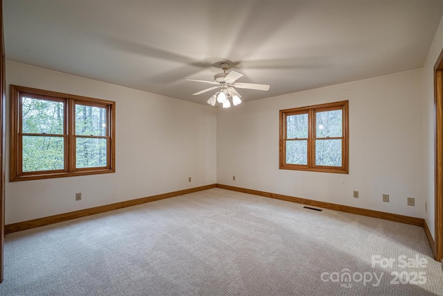 empty room featuring baseboards, ceiling fan, light carpet, and visible vents