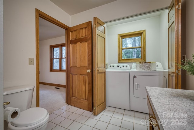clothes washing area featuring washer and clothes dryer, light carpet, and light tile patterned floors