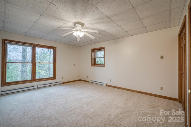 unfurnished room with a baseboard heating unit, a drop ceiling, and light carpet