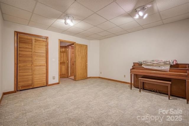 bedroom with tile patterned floors, baseboards, a closet, and a drop ceiling
