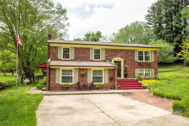 bi-level home with brick siding, a chimney, and a front yard