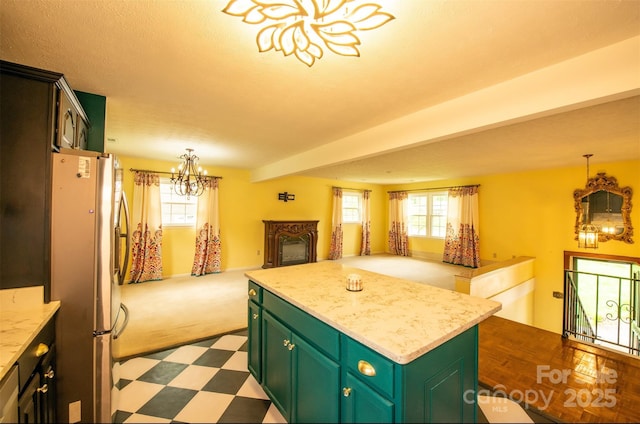 kitchen featuring light countertops, freestanding refrigerator, open floor plan, an inviting chandelier, and green cabinetry