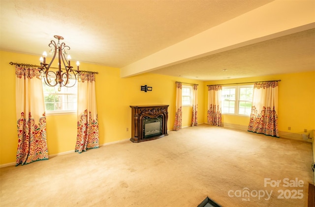 unfurnished living room featuring an inviting chandelier, baseboards, a fireplace, and carpet flooring