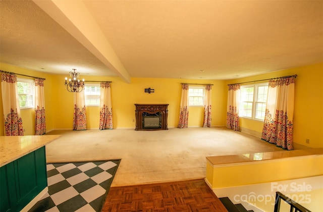 unfurnished living room featuring a healthy amount of sunlight, baseboards, a fireplace, and a chandelier