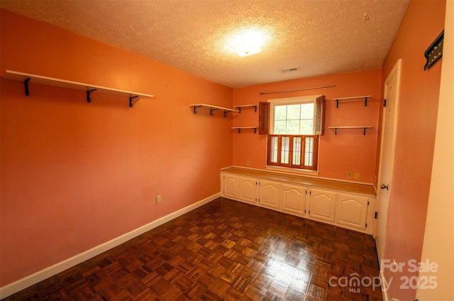 unfurnished room with baseboards, a textured ceiling, and visible vents