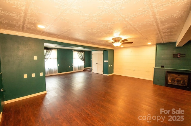 unfurnished living room featuring baseboards, a fireplace, a ceiling fan, and wood finished floors