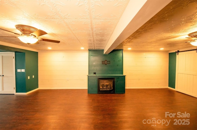 finished basement featuring baseboards, ceiling fan, wood finished floors, and a fireplace