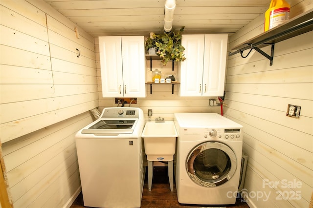 washroom with wooden walls, wooden ceiling, separate washer and dryer, a sink, and cabinet space