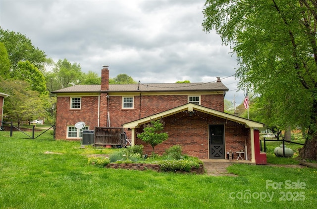 back of house with a lawn, central AC unit, brick siding, and a chimney