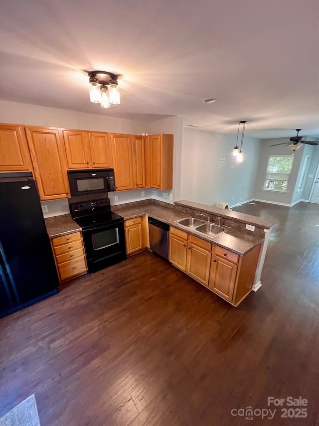kitchen featuring a peninsula, black appliances, dark countertops, and dark wood-style floors