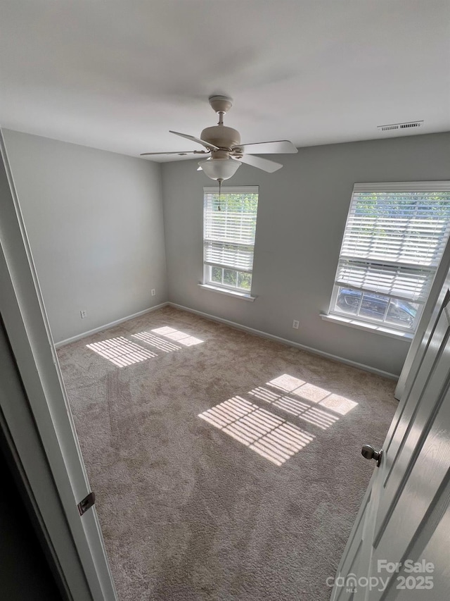 carpeted empty room featuring baseboards, a ceiling fan, and visible vents