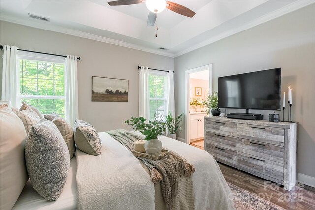 bedroom featuring visible vents, ornamental molding, connected bathroom, and wood finished floors