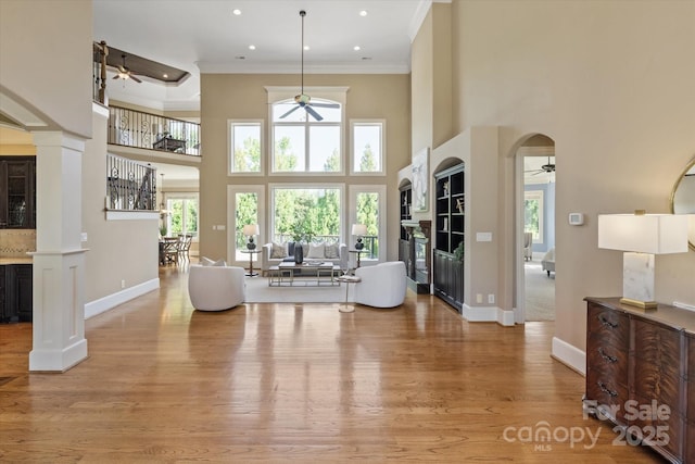 8904 Woodhall Lake Dr, Waxhaw, NC 28173 - living area featuring crown molding, ceiling fan, plenty of natural light, decorative columns, and a towering ceiling
