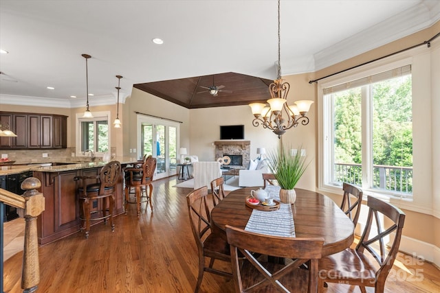 8904 Woodhall Lake Dr, Waxhaw, NC 28173 - dining space with a stone fireplace, ornamental molding, wood finished floors, and recessed lighting