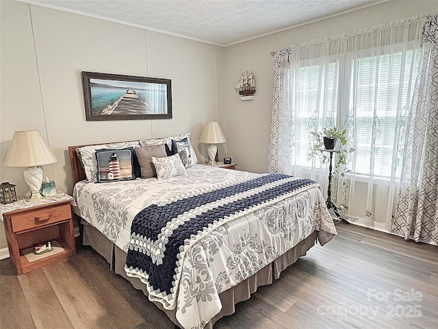 bedroom featuring crown molding, a textured ceiling, and wood finished floors
