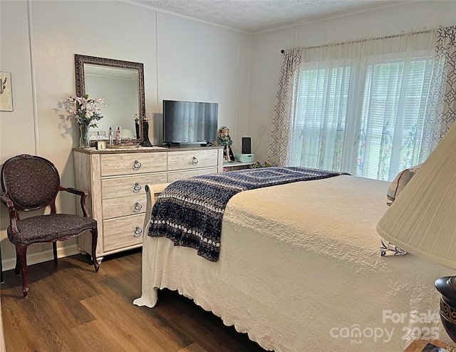 bedroom with dark wood-style flooring, a textured ceiling, and ornamental molding