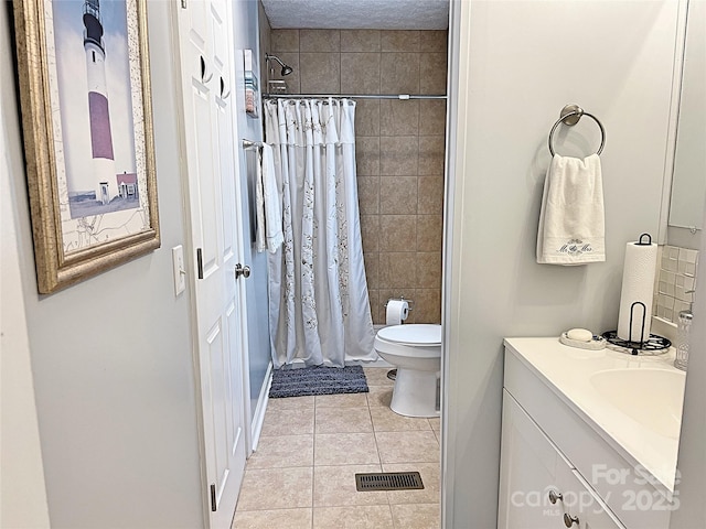 bathroom with vanity, tile patterned flooring, a tile shower, and toilet