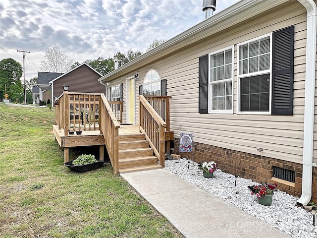 doorway to property featuring a yard, crawl space, and a deck