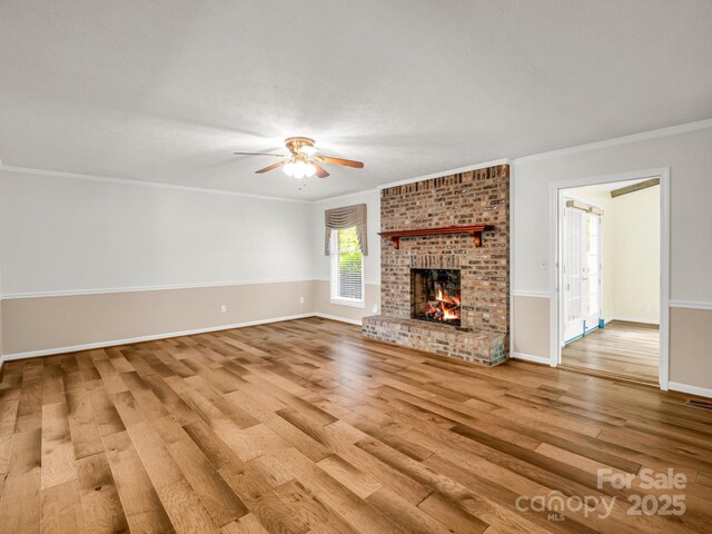 209 Daniel Dr, Hendersonville, NC 28739 - unfurnished living room featuring wood finished floors, crown molding, a ceiling fan, a brick fireplace, and baseboards