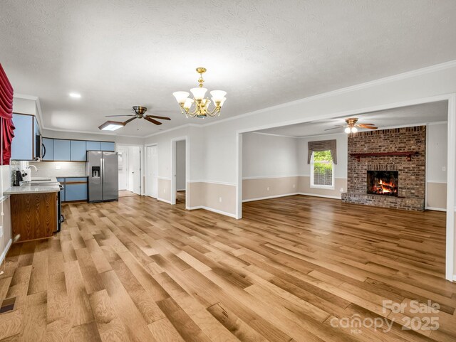 209 Daniel Dr, Hendersonville, NC 28739 - unfurnished living room featuring a ceiling fan, ornamental molding, light wood-style floors, a chandelier, and a textured ceiling