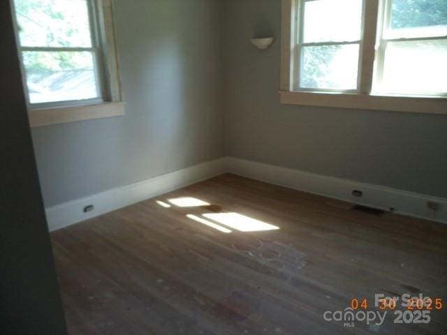 spare room featuring baseboards and wood finished floors