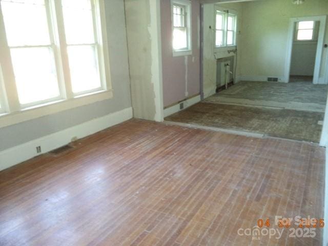 foyer entrance featuring visible vents, baseboards, wood finished floors, and a healthy amount of sunlight