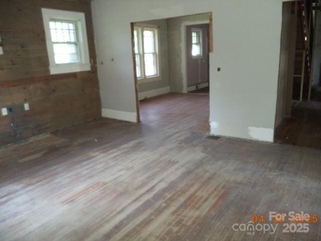 interior space featuring baseboards, wood walls, a healthy amount of sunlight, and wood finished floors