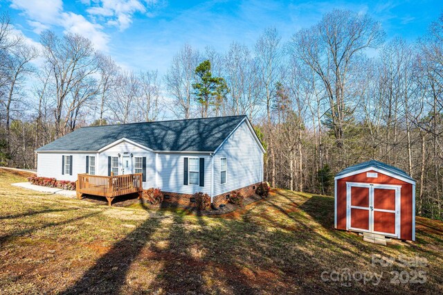 back of property featuring crawl space, a storage unit, a wooden deck, an outdoor structure, and a yard