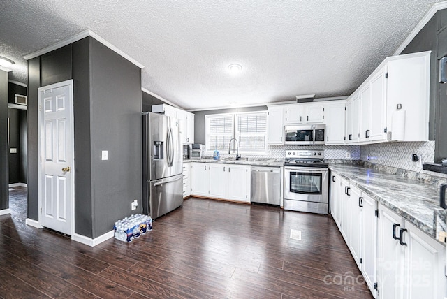 kitchen featuring stainless steel appliances, crown molding, a textured ceiling, white cabinets, and dark wood-style floors