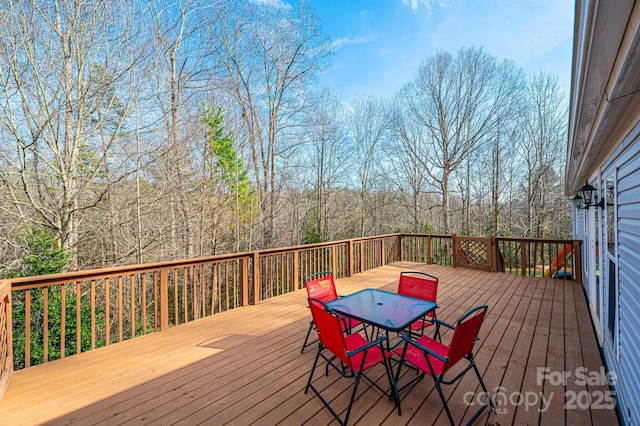 deck featuring outdoor dining area and a view of trees