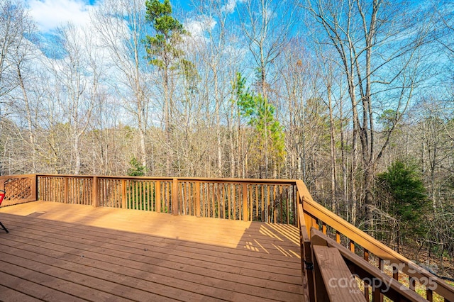 wooden terrace featuring a view of trees