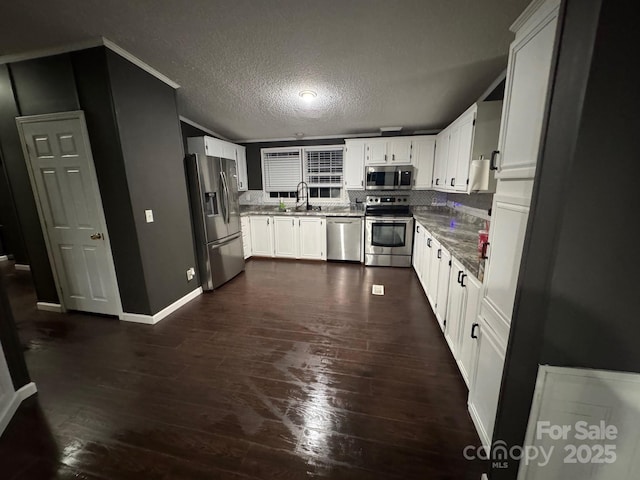 kitchen with stainless steel appliances, a sink, dark wood finished floors, tasteful backsplash, and a textured ceiling