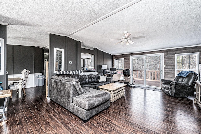 living room featuring a textured ceiling, a ceiling fan, wood finished floors, ornamental molding, and vaulted ceiling
