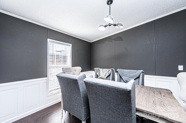 dining space featuring a decorative wall, crown molding, dark wood finished floors, a textured ceiling, and a chandelier