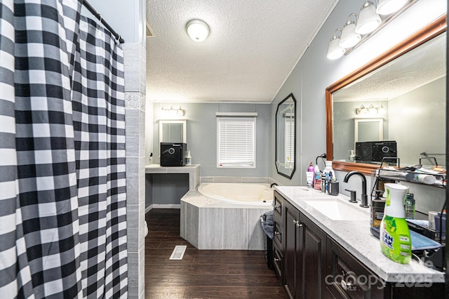 bathroom featuring a textured ceiling, wood finished floors, vanity, a bath, and a shower with shower curtain