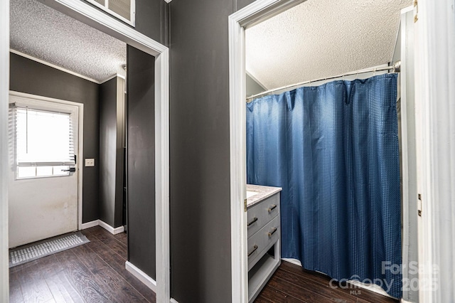bathroom featuring a textured ceiling, hardwood / wood-style floors, vanity, ornamental molding, and baseboards