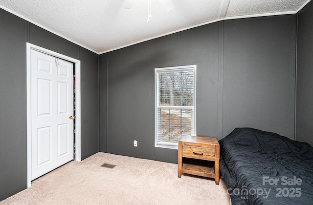 bedroom with carpet flooring, ceiling fan, a decorative wall, ornamental molding, and a textured ceiling