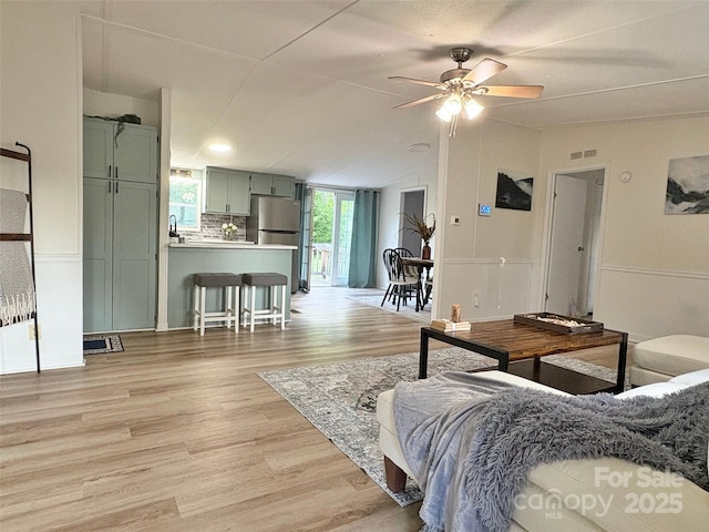 living area featuring visible vents, a ceiling fan, light wood-style flooring, and lofted ceiling