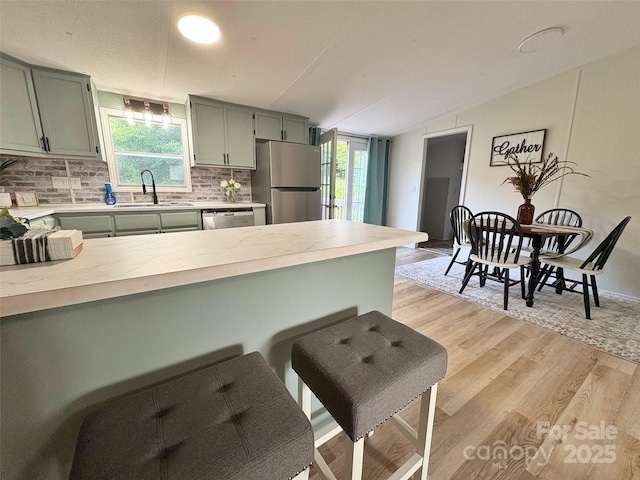 kitchen featuring a sink, appliances with stainless steel finishes, green cabinets, and light countertops