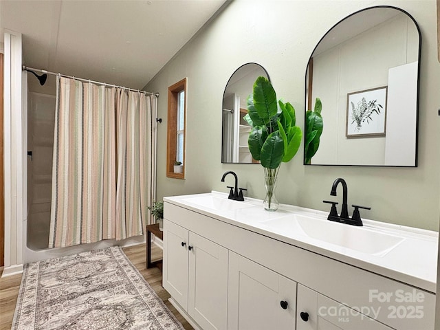 bathroom featuring double vanity, a sink, and wood finished floors