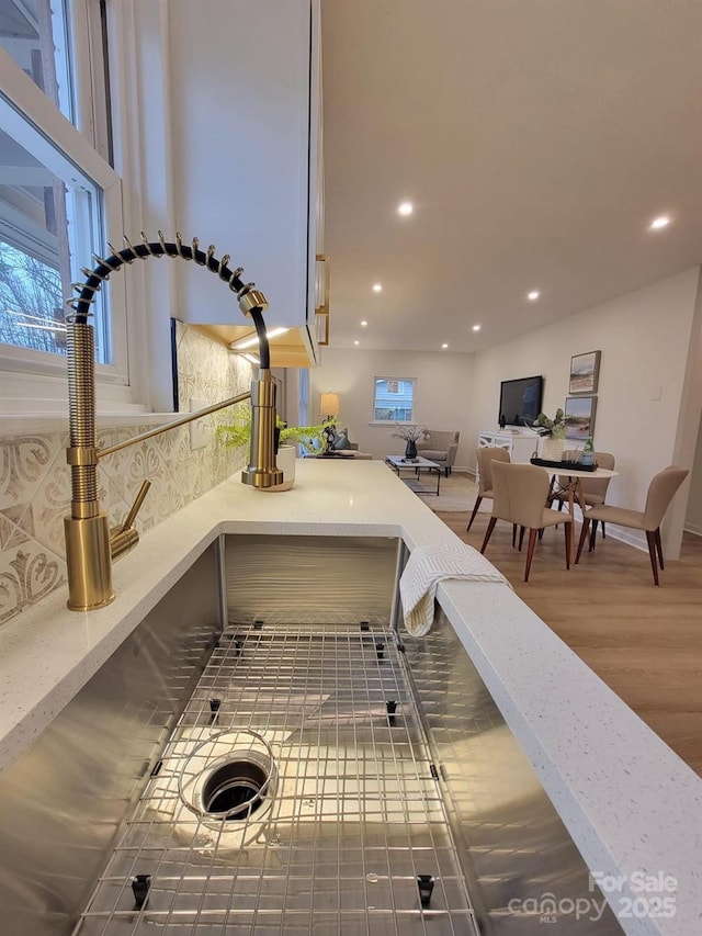 room details featuring a sink, backsplash, recessed lighting, and wood finished floors