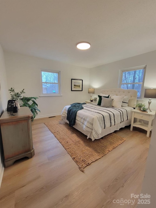 bedroom with baseboards, visible vents, and light wood-style flooring