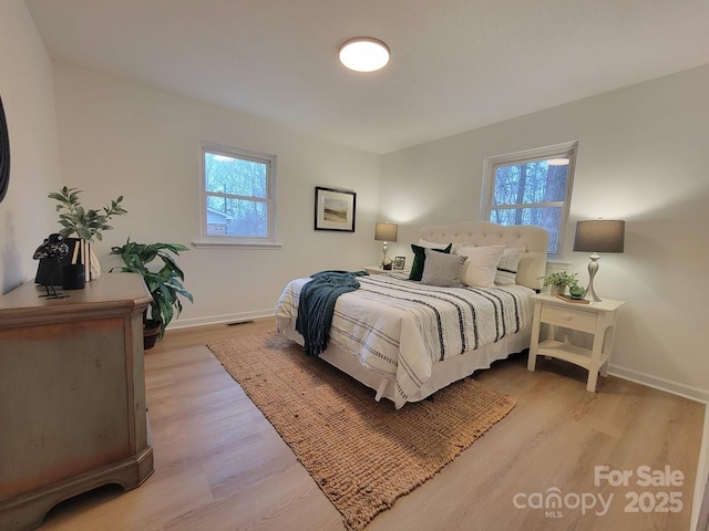 bedroom with baseboards, light wood-style flooring, and multiple windows