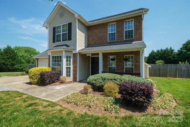 traditional-style house with brick siding, a garage, a front lawn, and fence